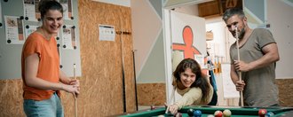 Fachklinik Grafrath Zwei Frauen und ein Mann spielen Billard.